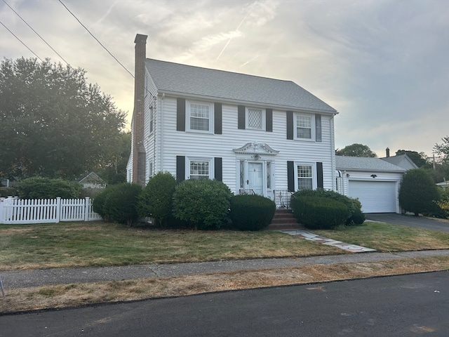 colonial inspired home featuring a front yard and a garage