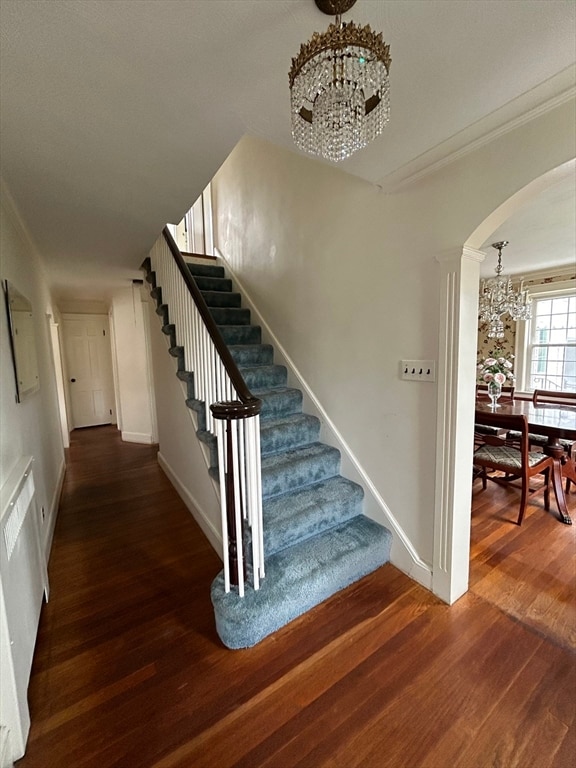 stairway featuring ornamental molding, a notable chandelier, and hardwood / wood-style floors