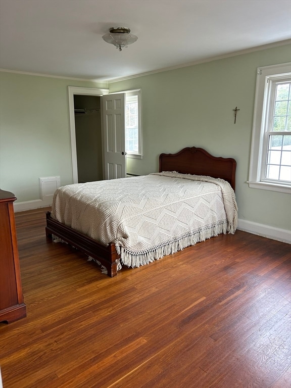 bedroom with ornamental molding and dark hardwood / wood-style floors