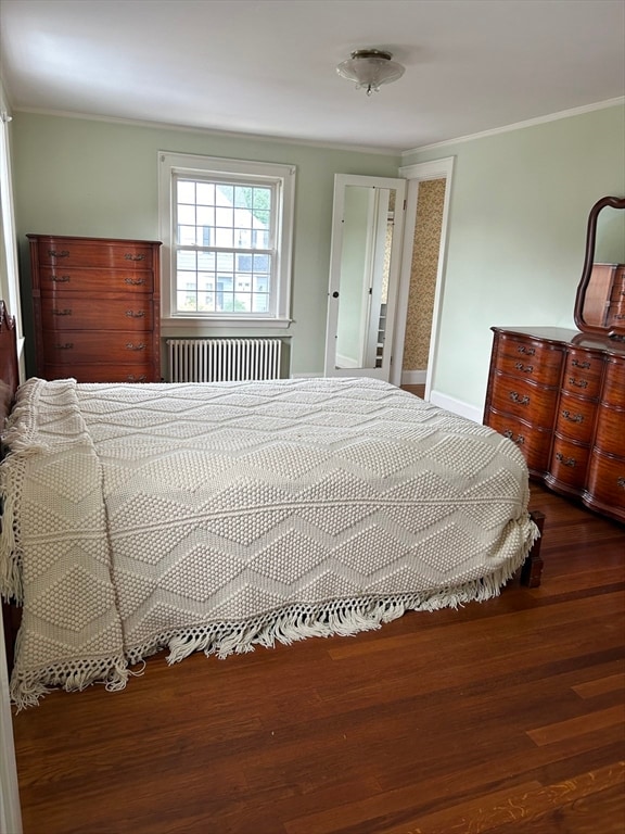 bedroom with radiator heating unit, ornamental molding, and dark wood-type flooring