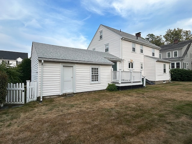 back of property featuring a lawn and a wooden deck