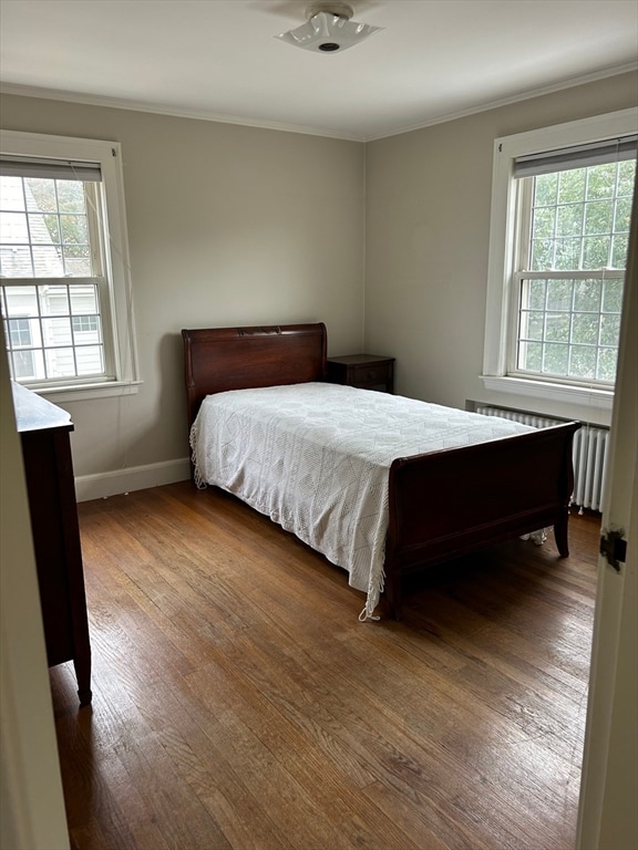 bedroom with radiator, dark hardwood / wood-style floors, and crown molding