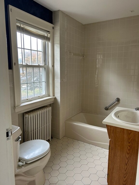 full bathroom with vanity, tile walls, toilet, and radiator heating unit