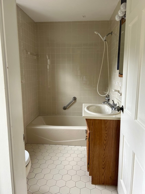 full bathroom with tiled shower / bath combo, tile patterned flooring, vanity, and toilet