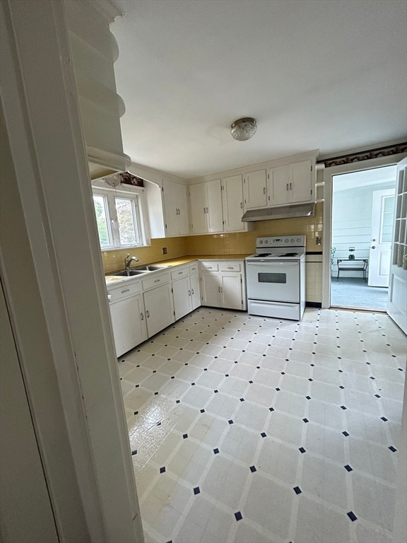 kitchen with white cabinetry, electric stove, sink, and tasteful backsplash