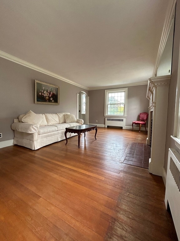 unfurnished living room with radiator heating unit, dark hardwood / wood-style floors, and crown molding