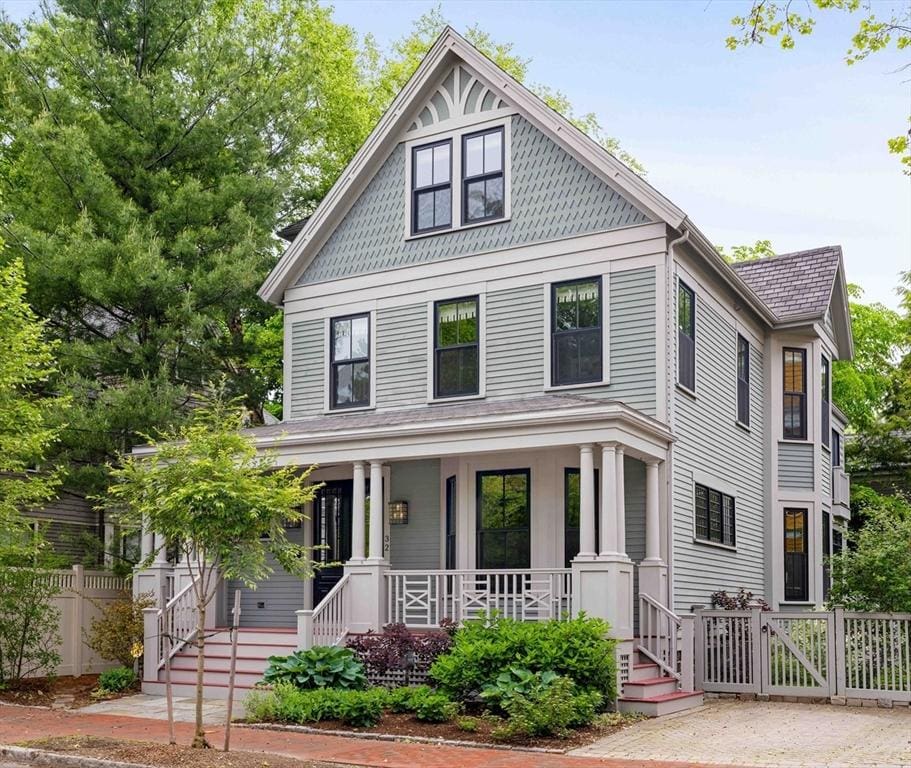 victorian-style house featuring a porch, fence, and a gate