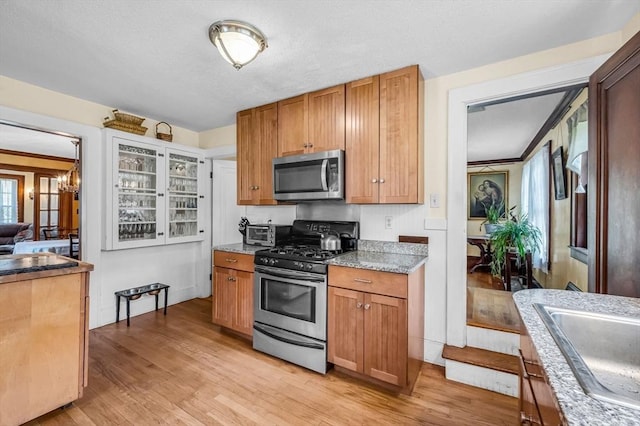 68 Ingersoll Grv, Springfield, MA 01109 - kitchen with light stone countertops, an inviting chandelier, a sink, light wood-style flooring, and stainless steel appliances