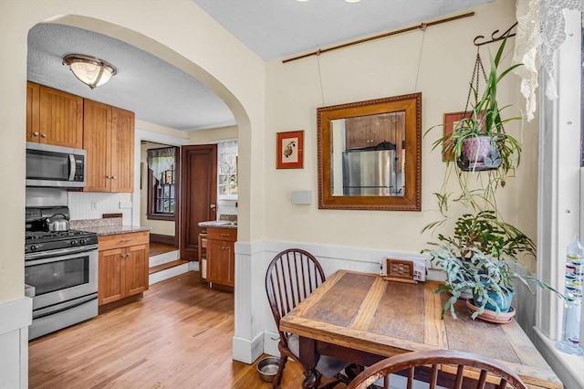 68 Ingersoll Grv, Springfield, MA 01109 - kitchen with arched walkways, light wood-style flooring, appliances with stainless steel finishes, and brown cabinets
