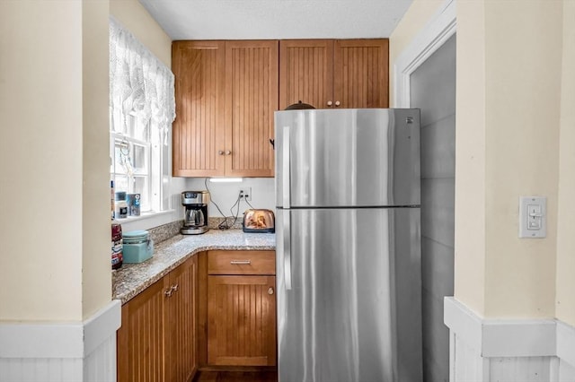 68 Ingersoll Grv, Springfield, MA 01109 - kitchen featuring light stone counters, freestanding refrigerator, and brown cabinets