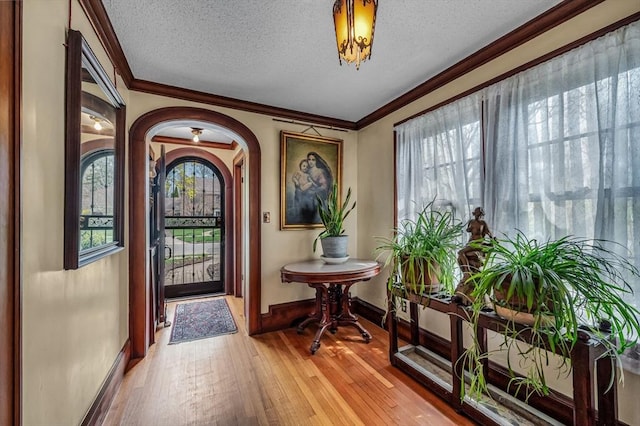 68 Ingersoll Grv, Springfield, MA 01109 - entrance foyer featuring light wood-style floors, arched walkways, a textured ceiling, baseboards, and ornamental molding