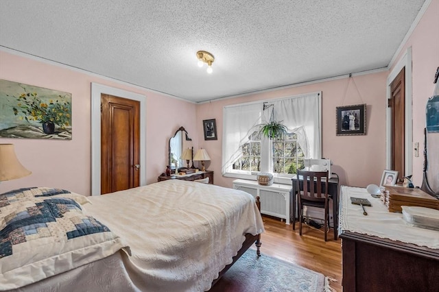 68 Ingersoll Grv, Springfield, MA 01109 - bedroom with radiator heating unit, a textured ceiling, crown molding, and wood finished floors