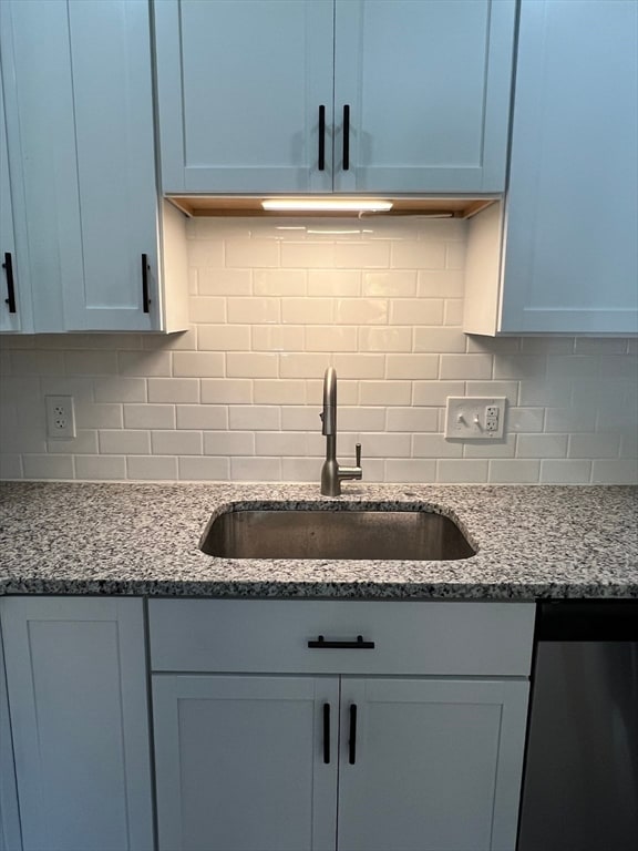 kitchen featuring light stone countertops, decorative backsplash, dishwasher, and sink