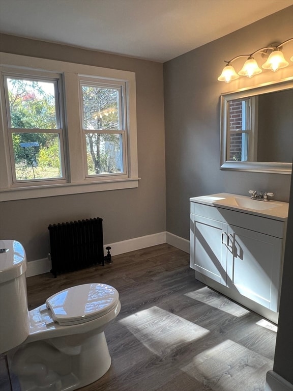 bathroom featuring radiator heating unit, vanity, wood-type flooring, and toilet