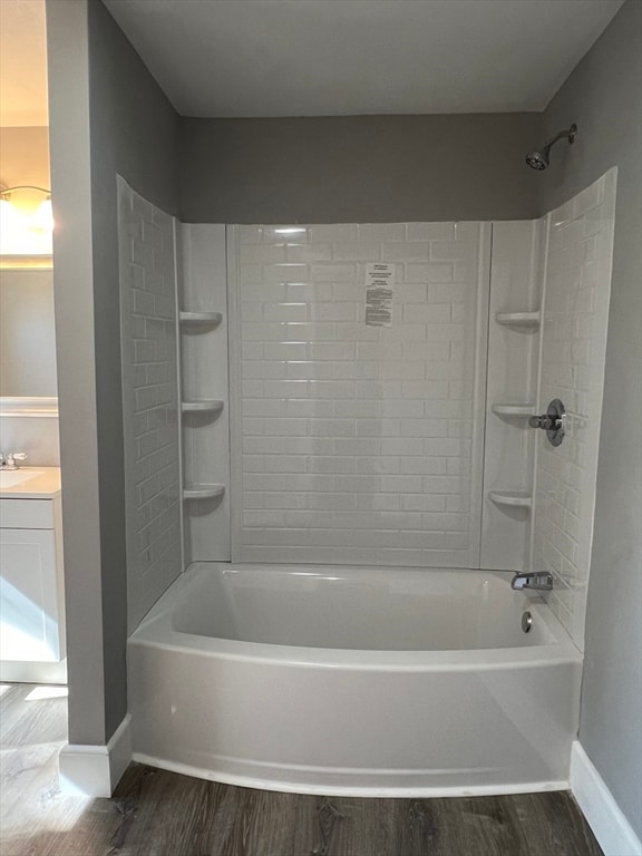 bathroom with hardwood / wood-style flooring, vanity, and tiled shower / bath