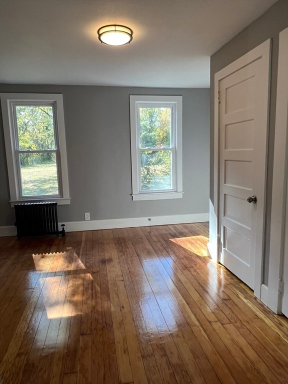 empty room with radiator, a wealth of natural light, and wood-type flooring