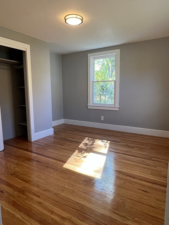 unfurnished bedroom with dark hardwood / wood-style flooring and a closet