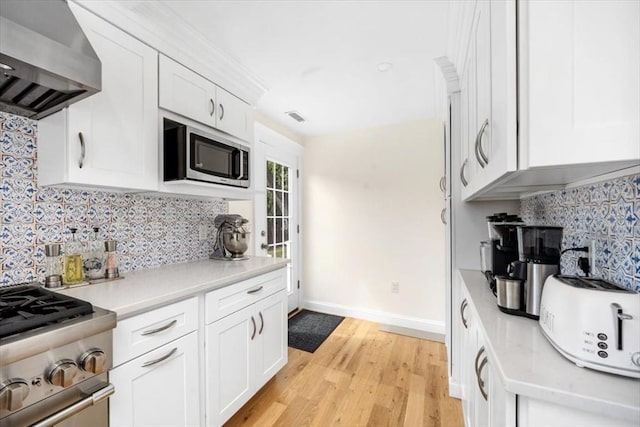 4 Cushing St, Hingham, MA 02043 - kitchen with wall chimney range hood, appliances with stainless steel finishes, light wood-style flooring, backsplash, and baseboards