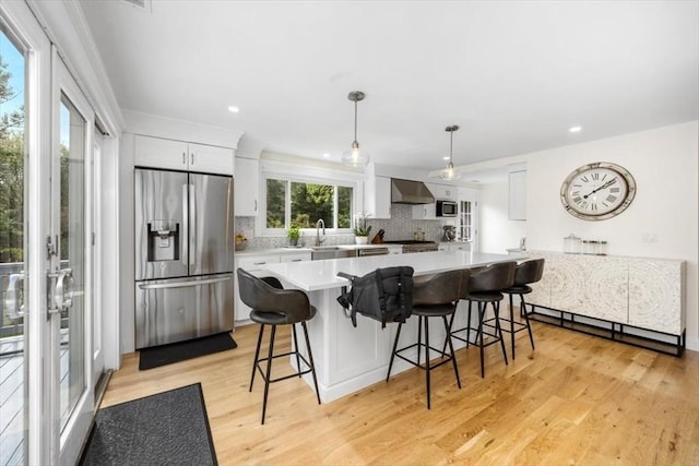 4 Cushing St, Hingham, MA 02043 - kitchen featuring appliances with stainless steel finishes, wall chimney range hood, backsplash, light wood finished floors, and recessed lighting