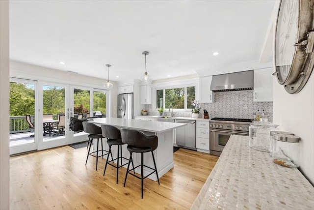 4 Cushing St, Hingham, MA 02043 - kitchen with appliances with stainless steel finishes, wall chimney exhaust hood, light wood-style floors, a kitchen bar, and tasteful backsplash