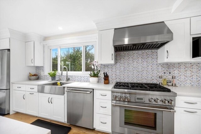 4 Cushing St, Hingham, MA 02043 - kitchen with stainless steel appliances, wall chimney exhaust hood, a sink, and light countertops