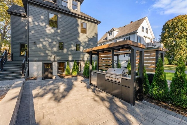 rear view of house with exterior kitchen, stairs, and a patio
