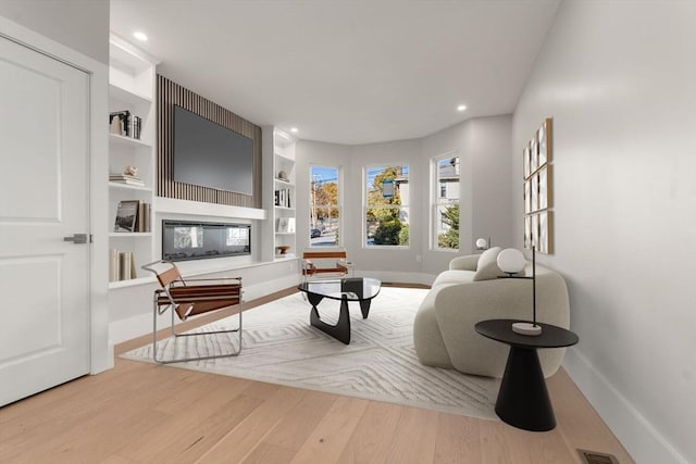 living room featuring baseboards, wood finished floors, recessed lighting, and built in features