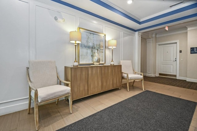 sitting room with ornamental molding and a tray ceiling