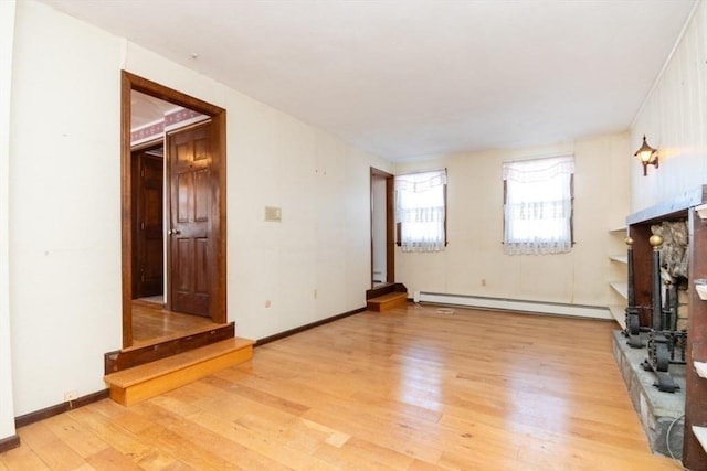 unfurnished living room with a baseboard heating unit and light hardwood / wood-style flooring