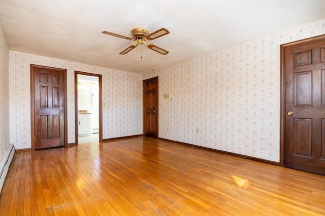 unfurnished bedroom featuring ceiling fan, wood-type flooring, ensuite bathroom, and a baseboard heating unit