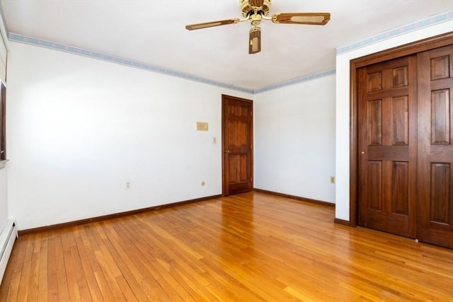 unfurnished bedroom with ceiling fan, light hardwood / wood-style flooring, and a baseboard heating unit