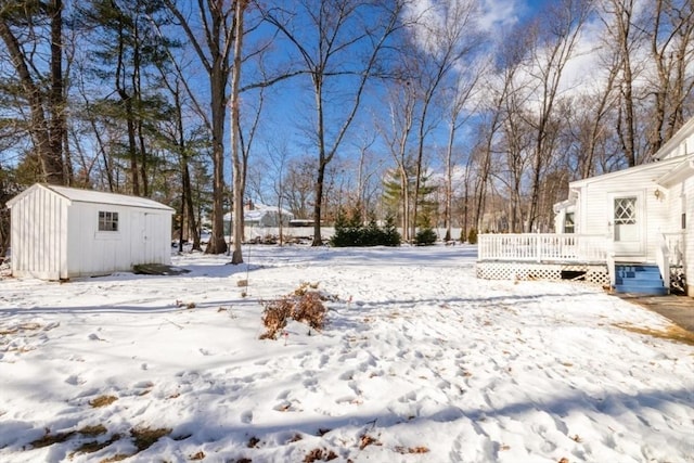 yard covered in snow featuring a storage shed and a deck