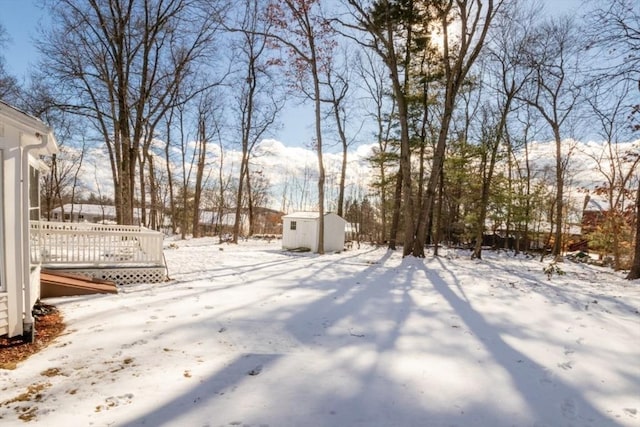 yard covered in snow featuring a deck and a storage unit