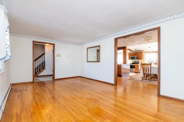 unfurnished living room featuring crown molding, light wood-type flooring, and baseboard heating