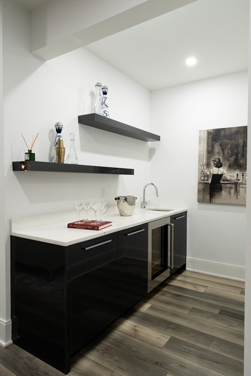 bar with beverage cooler, dark wood-type flooring, and sink