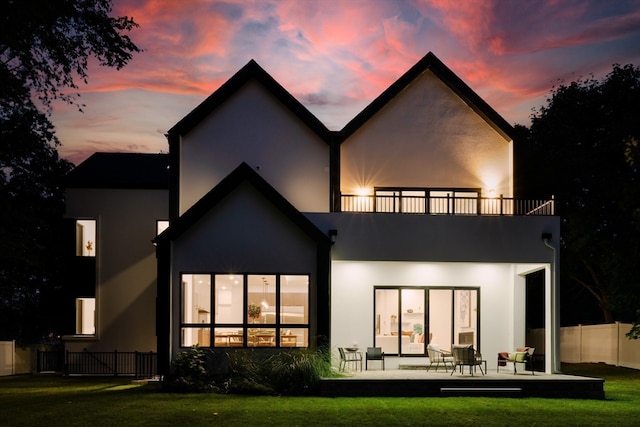 back house at dusk with a patio and a yard