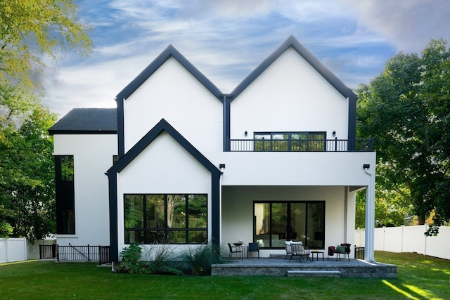 rear view of house with a lawn, a balcony, and a patio area