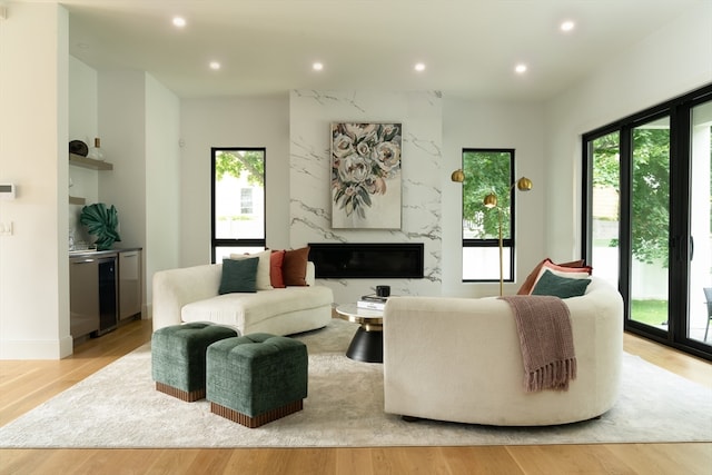 living room with light hardwood / wood-style flooring, a high end fireplace, and plenty of natural light