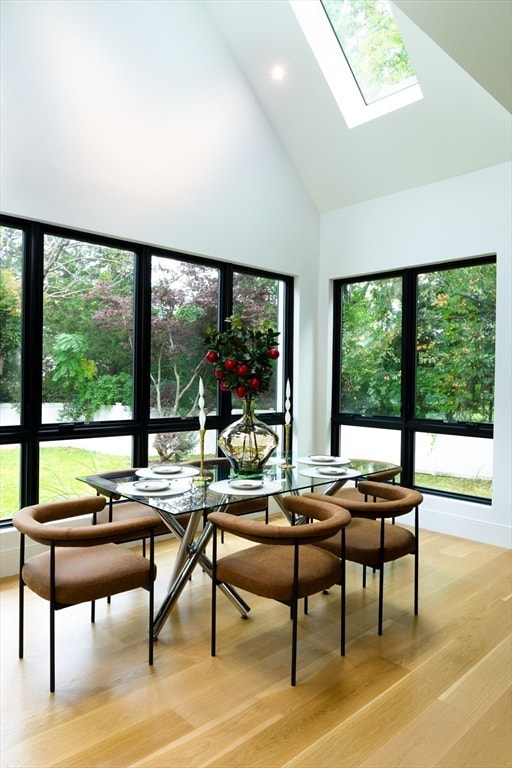 dining space with a healthy amount of sunlight, light hardwood / wood-style flooring, and high vaulted ceiling