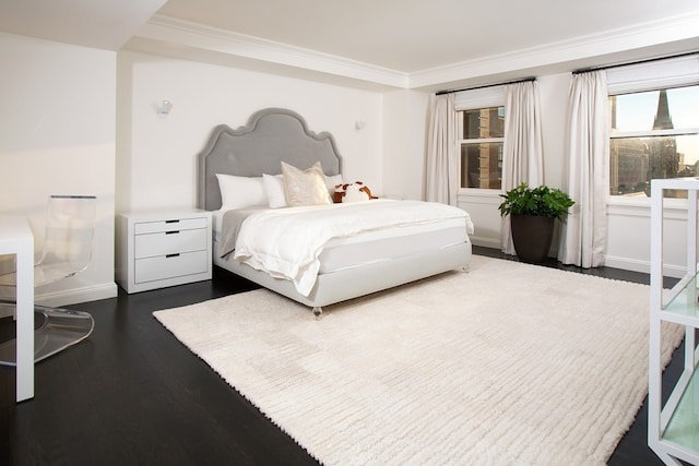 bedroom with dark wood-type flooring, ornamental molding, and baseboards