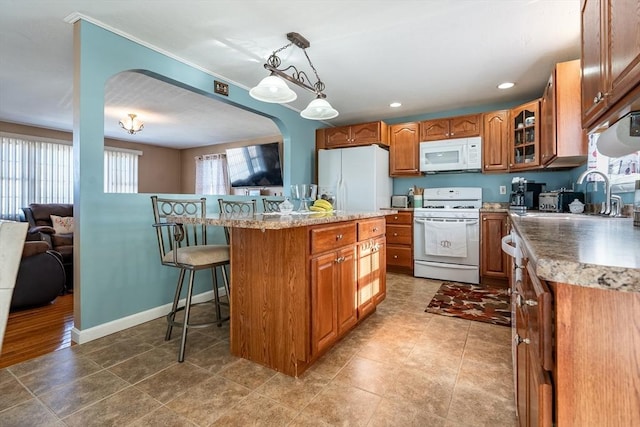 kitchen featuring a breakfast bar, a kitchen island, sink, white appliances, and pendant lighting