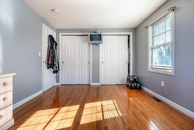 unfurnished bedroom with wood-type flooring and two closets