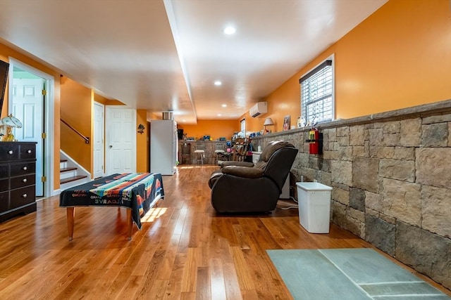 rec room featuring a wall unit AC and light hardwood / wood-style floors