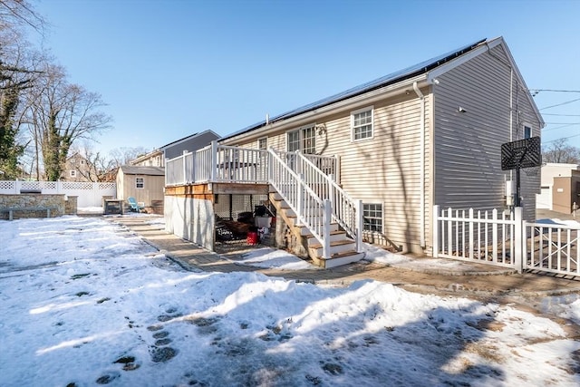 snow covered house featuring a shed and a deck