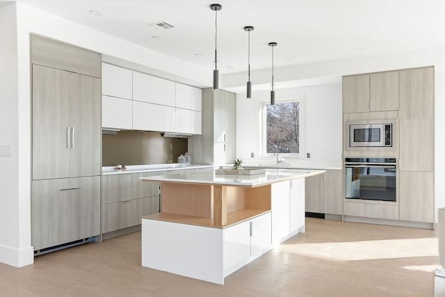 kitchen with pendant lighting, white cabinetry, a center island, built in appliances, and light wood-type flooring