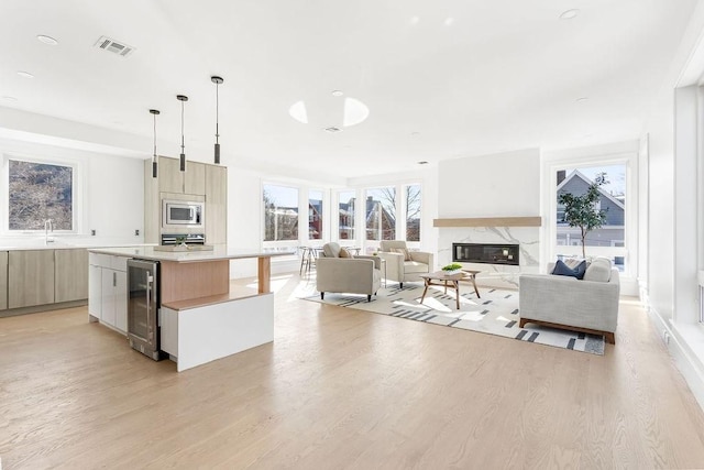 kitchen featuring wine cooler, a center island, hanging light fixtures, stainless steel microwave, and a fireplace