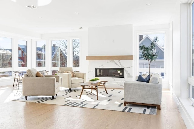 living room with a high end fireplace and light wood-type flooring