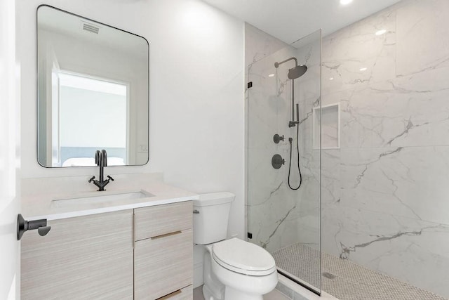 bathroom with tiled shower, vanity, and toilet