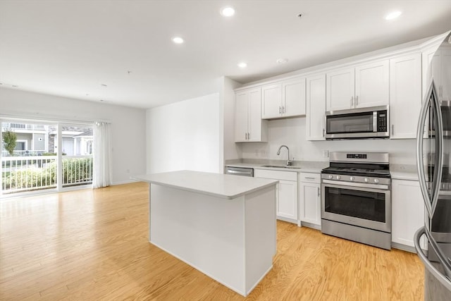 kitchen with a center island, sink, light hardwood / wood-style flooring, white cabinetry, and stainless steel appliances