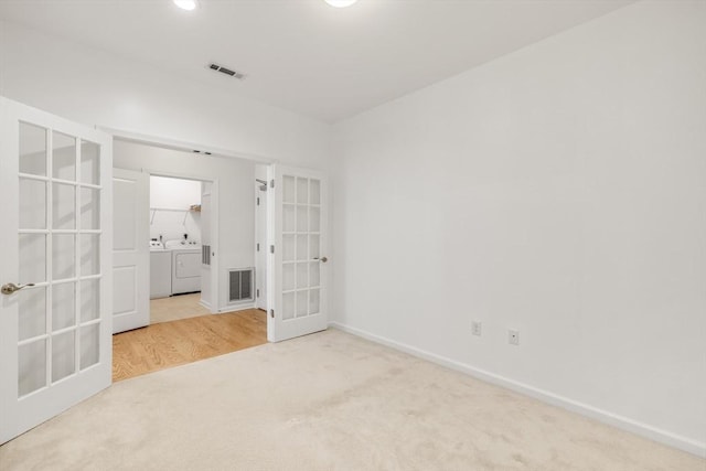 spare room with carpet flooring, french doors, and independent washer and dryer